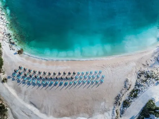 Rajska plaża na Thassos z turkusową wodą i rzędami leżaków. Idealne miejsce na relaks i podziwianie pięknych widoków.