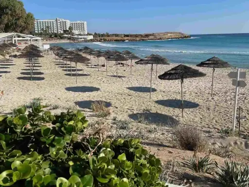 Plaże Cypru Północnego z rzędami parasoli i hotelami w tle.