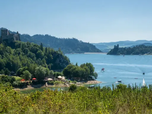 Malowniczy park krajobrazowy Małopolska z zamkiem na wzgórzu, jeziorem i łodziami.