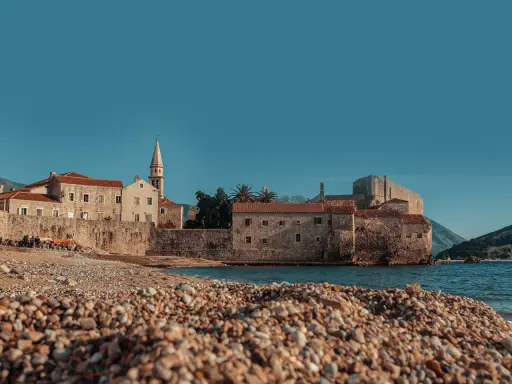 Kamienista plaża w Budvie, z widokiem na starówkę i morze. Idealne miejsce, by zastanowić się, jak dojechać z Podgoricy do Budvy.