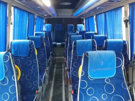 Wygodne siedzenia w autobusie, idealne na transport między Tiraną a Durrës. Błękitne zasłony i wzorzyste obicia dodają uroku.