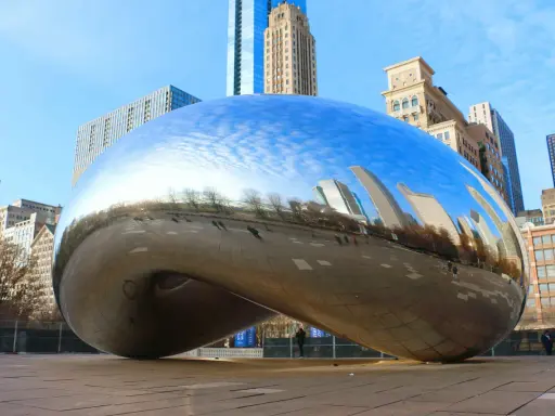 Chicagowskie atrakcje i okolice: Błyszcząca fasola Cloud Gate odbija drapacze chmur i błękitne niebo.