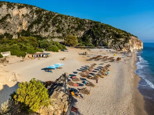 Piękne albania plaże z rzędami leżaków i parasoli, skaliste zbocze i turkusowe morze.