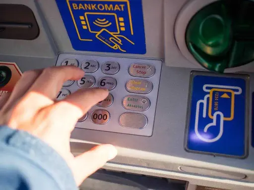 Dłoń wpisuje PIN na bankomacie w Turcji. Szukaj bankomatów bez prowizji, by oszczędzić na wakacjach.