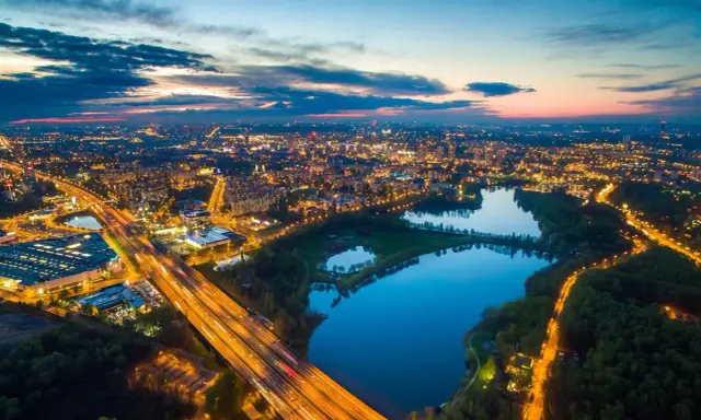 Wieczorny widok na rozświetlone miasto i trzy stawy w Dolinie Trzech Stawów w Katowicach.