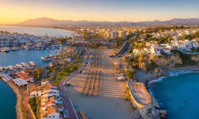 Widok na port jachtowy i plażę w słoneczny dzień. Idealne miejsce, by odkryć, co warto zobaczyć na Costa del Sol.