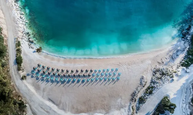 Rajska plaża na Thassos z turkusową wodą i rzędami leżaków. Idealne miejsce na relaks i podziwianie pięknych widoków.