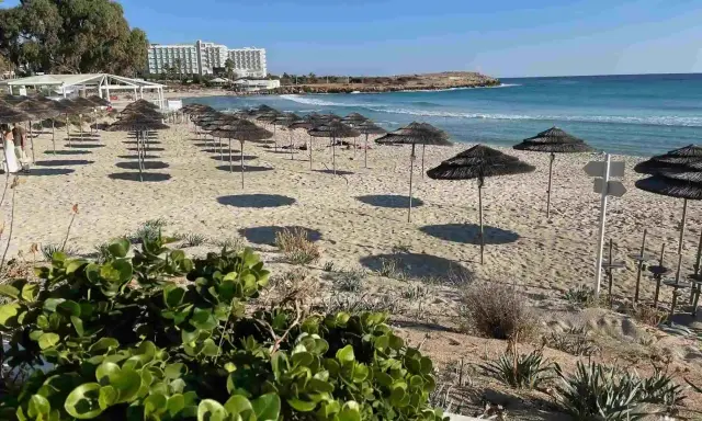 Plaże Cypru Północnego z rzędami parasoli i hotelami w tle.