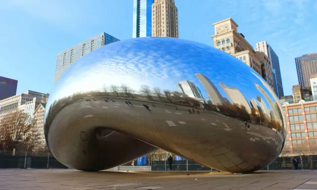 Chicagowskie atrakcje i okolice: Błyszcząca fasola Cloud Gate odbija drapacze chmur i błękitne niebo.
