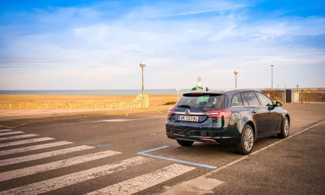 Ciemny kombi zaparkowany przy plaży, gotowy na długą trasę Polska-Hiszpania samochodem.