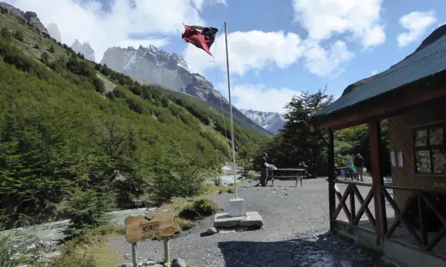 Wspaniałe widoki w Chile! Flaga powiewa nad chatką, a w tle majestatyczne góry. Idealne miejsce, by zobaczyć cuda natury.
