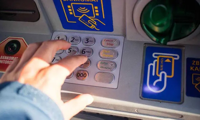 Dłoń wpisuje PIN na bankomacie w Turcji. Szukaj bankomatów bez prowizji, by oszczędzić na wakacjach.