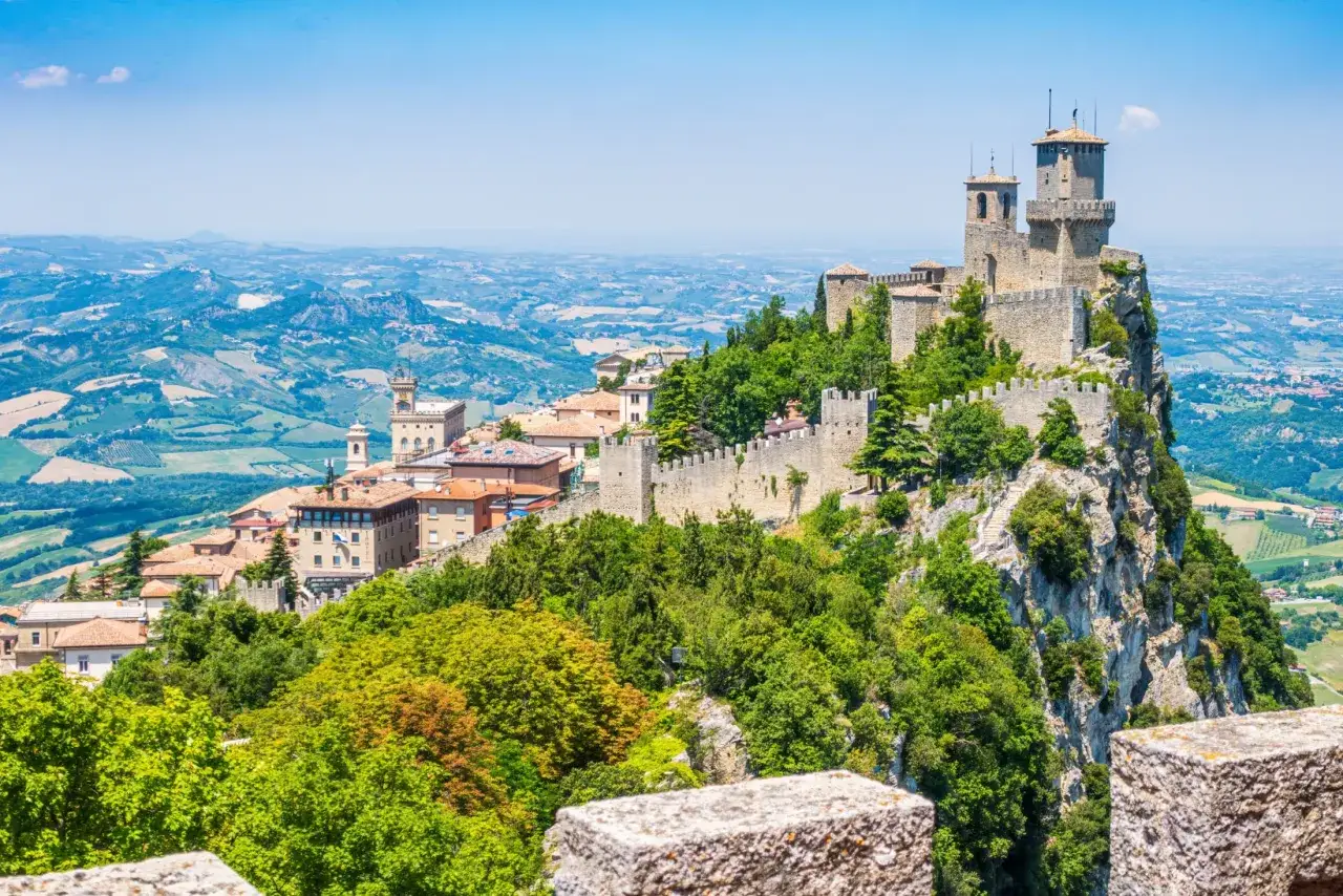 Trzy wieże obronne górują nad malowniczym krajobrazem San Marino, otoczone zielenią i historyczną zabudową.