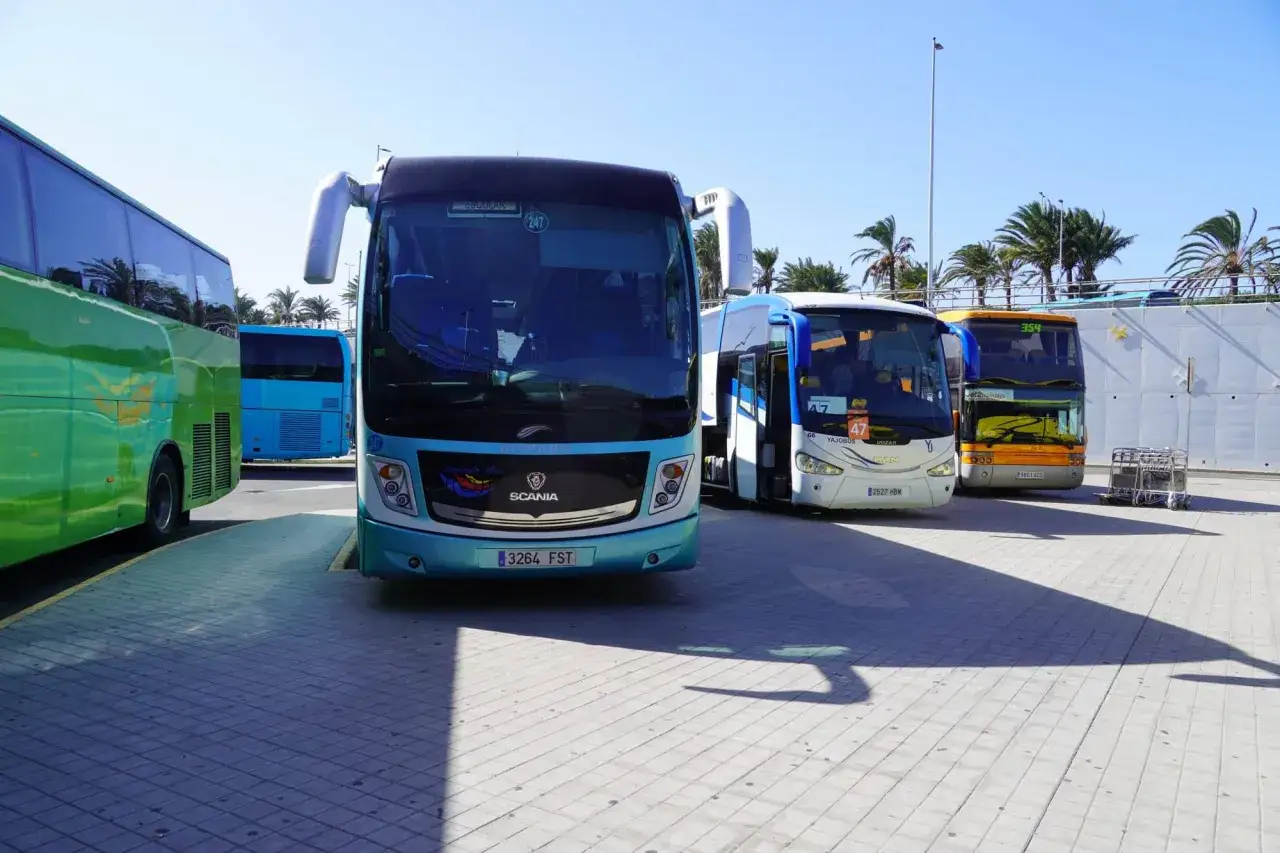 Kilka autobusów, w tym zielony, niebieski i turkusowy, stoi na parkingu na Gran Canarii.