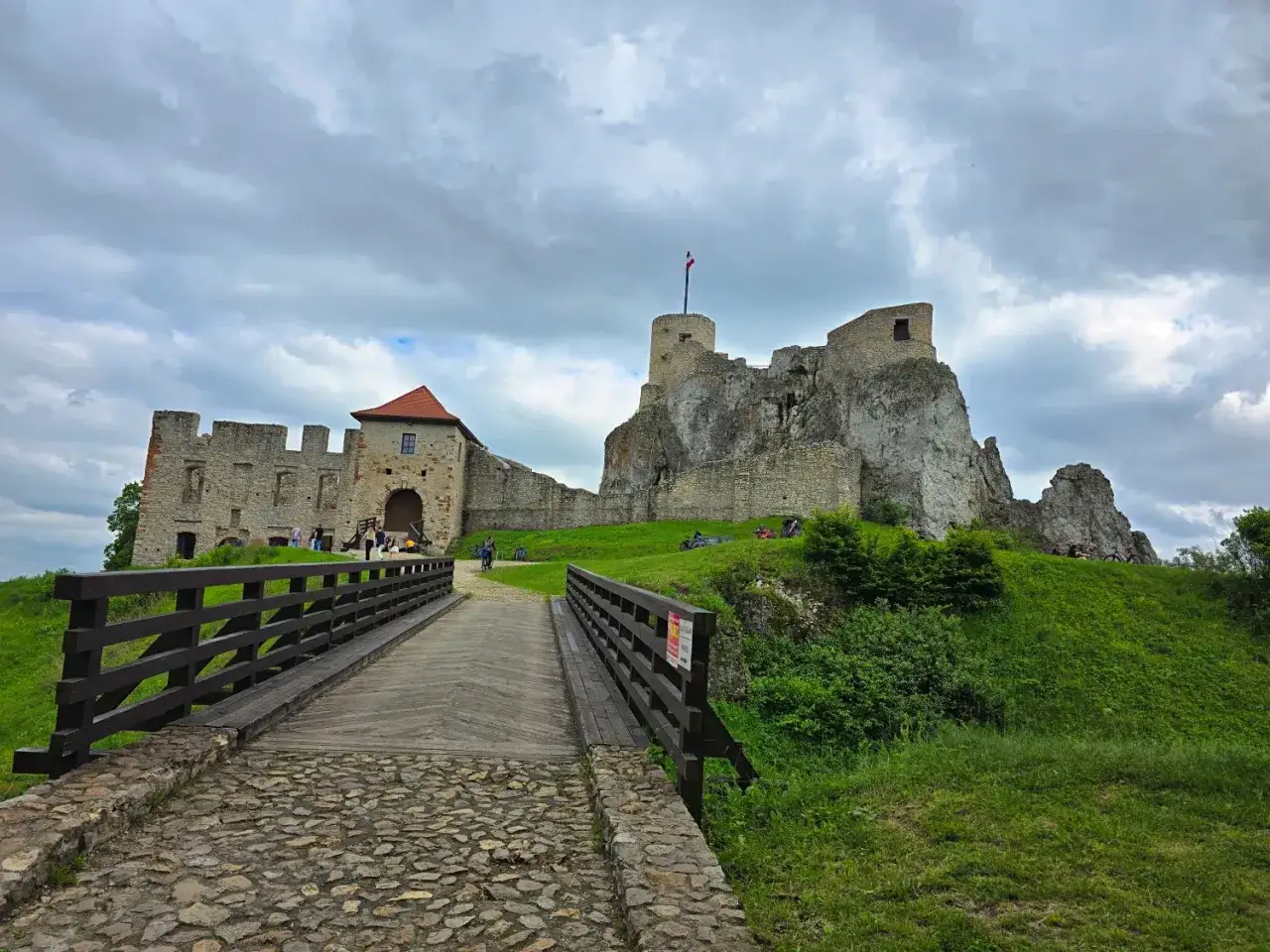 Kamienny most prowadzi do ruin zamku, gdzie w oddali widać wieżę. Chata Kocjana, jak ją nazywają, stoi na wzgórzu.