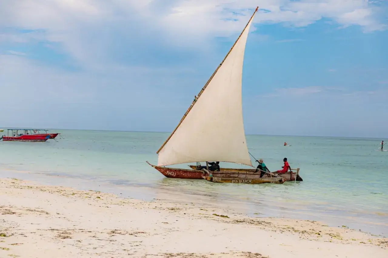 Tradycyjna łódź z żaglem na turkusowej wodzie, jedna z wielu atrakcji Zanzibaru.