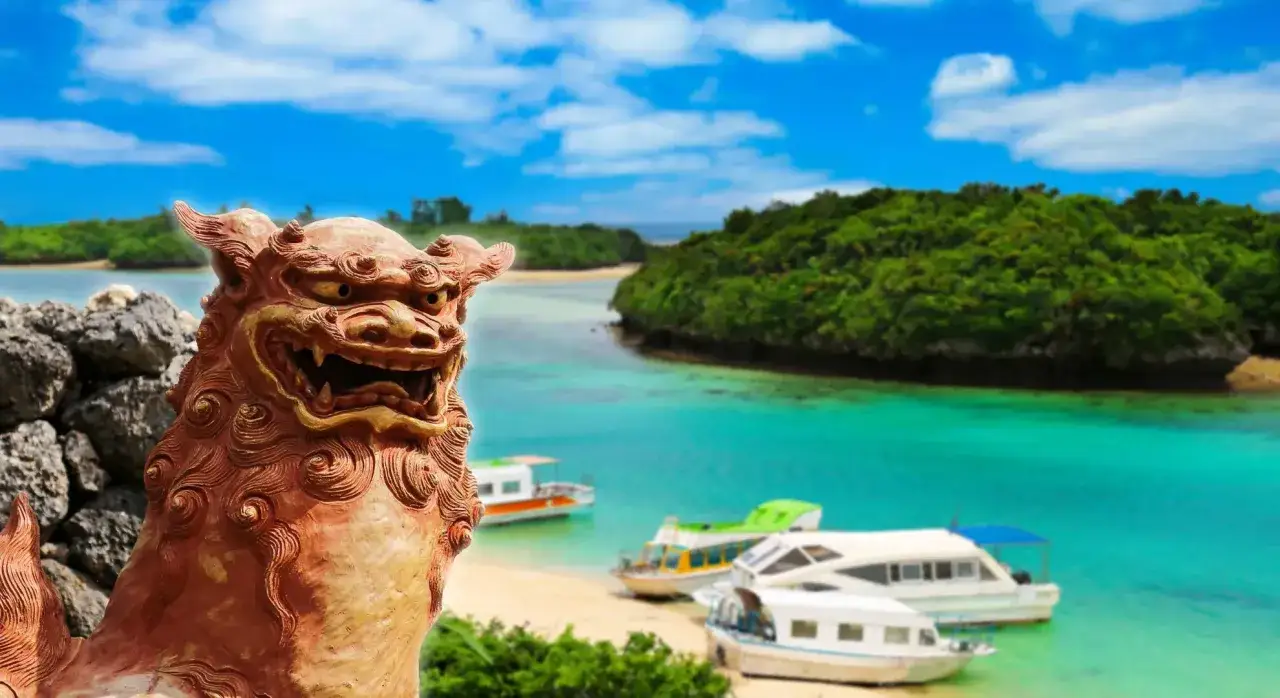 Kamienna lwica strzeże rajskiej plaży z turkusową wodą i łodziami na Okinawie w Japonii.