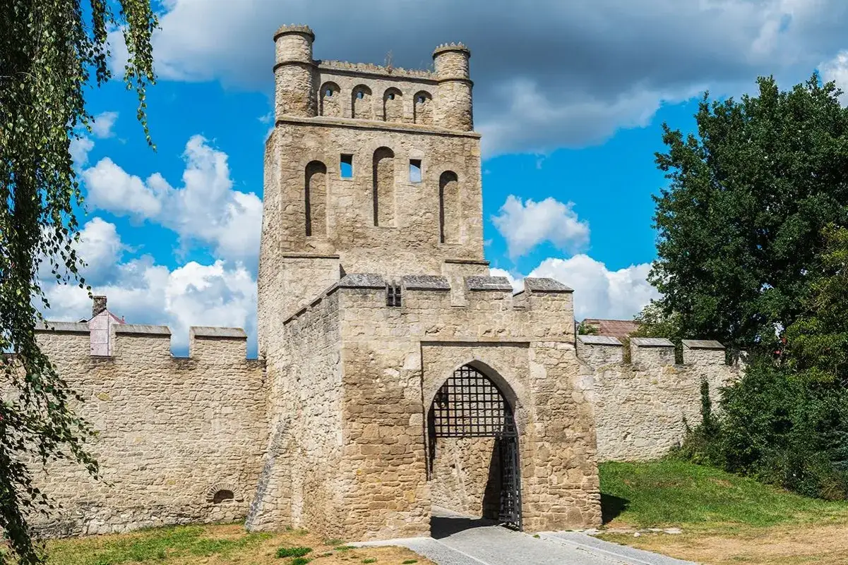Kamienny zamek z bramą i wieżą, jeden z zamków w okolicach Jaworzna, pod błękitnym niebem z chmurami.
