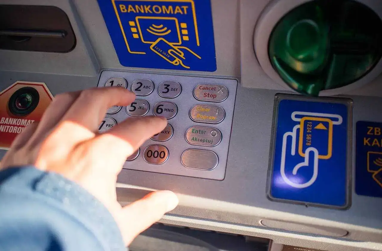 Ręka wpisuje PIN na bankomacie w Turcji. Szukaj bankomatów bez prowizji, by podróżować taniej!