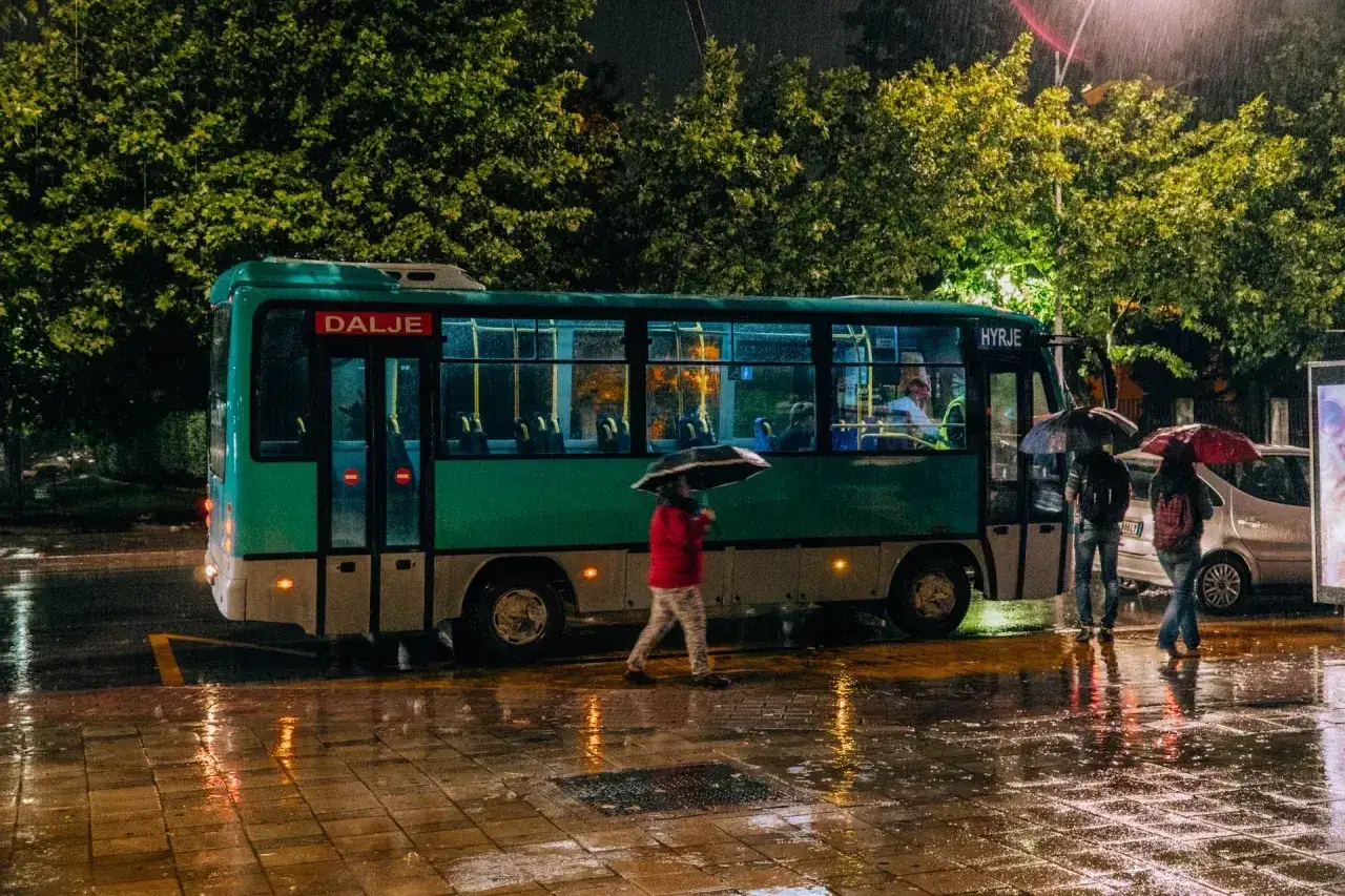 Nocny deszcz w Tiranie. Autobus z napisem 