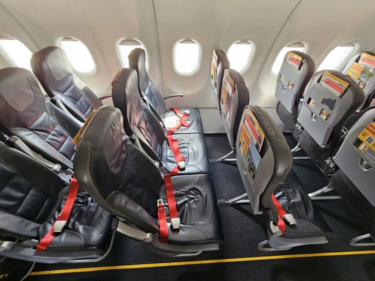 Puste fotele w samolocie Pegasus Airlines, gotowe na odprawę. Czerwone pasy bezpieczeństwa czekają na pasażerów.