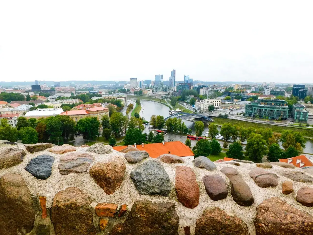 Widok na Wilno z murów obronnych. Rzeka Wilejka przecina miasto, a w oddali widać nowoczesne budynki.