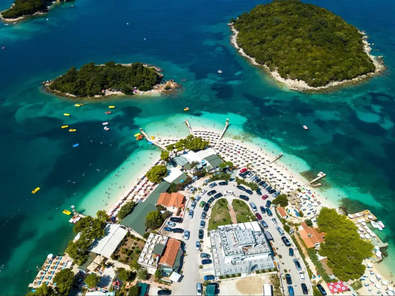 Rajskie albania plaże z turkusową wodą, zielonymi wysepkami i mnóstwem leżaków.