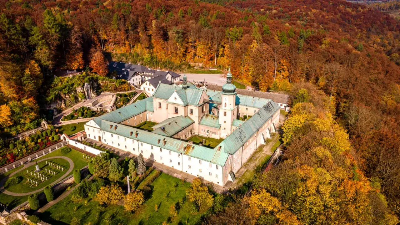 Malowniczy widok na klasztor na tle jesiennych lasów. Czerna klasztor otoczony kolorowymi drzewami, z zadbanym ogrodem i cmentarzem.
