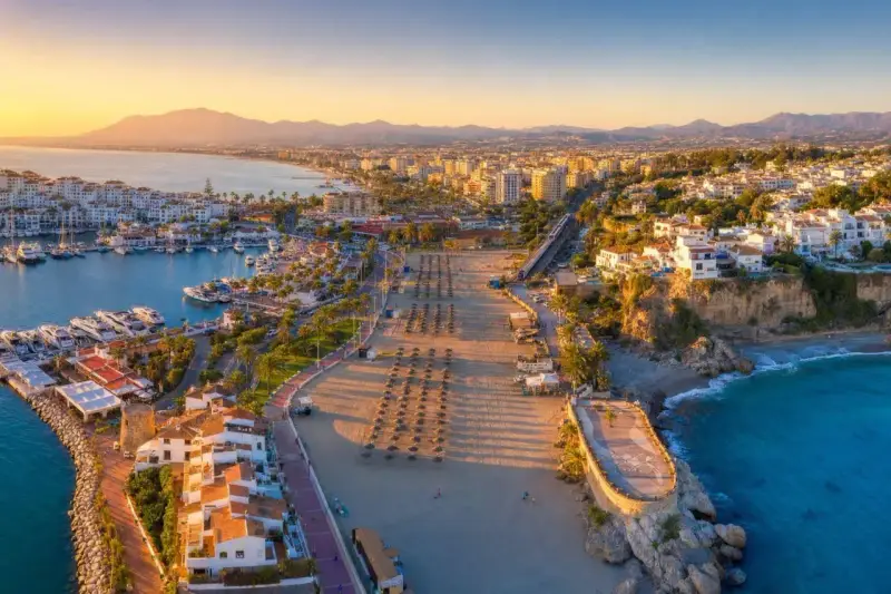 Widok na port jachtowy i plażę w słoneczny dzień. Idealne miejsce, by odkryć, co warto zobaczyć na Costa del Sol.